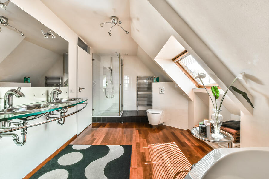 Aerial view of a house with a shingled roof, a backyard patio with outdoor furniture, and surrounded by trees and green lawn.